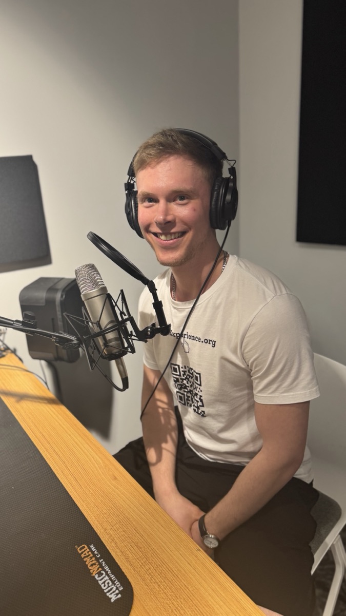 Olivier smiling at a microphone in a recording studio